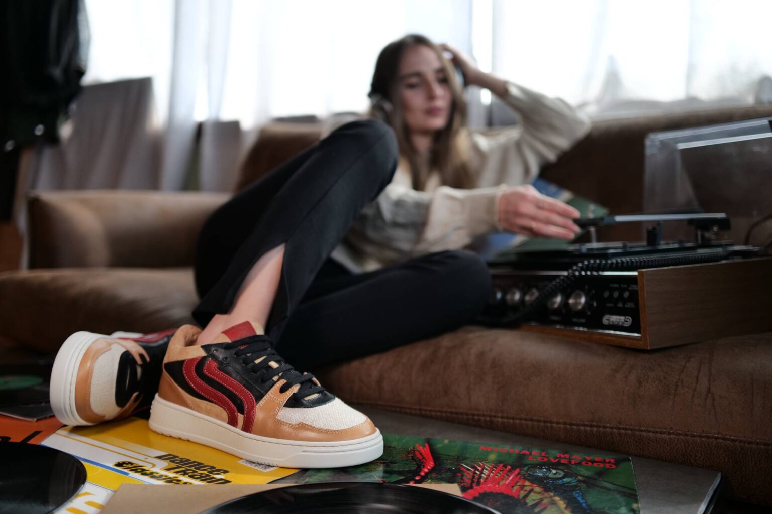 Ragazza con sneaker Sneark su un divano con giradischi